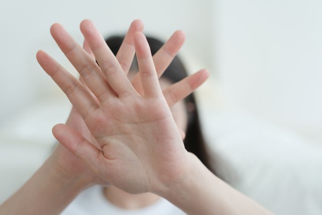 顔の前で手のひらを交差する女性