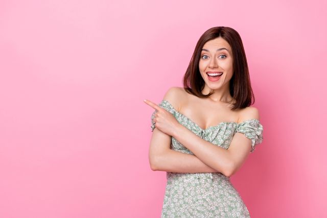 横を指さす女性